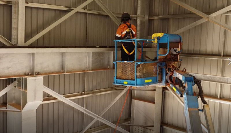 Worker using a crane and fixing a the industrial roof