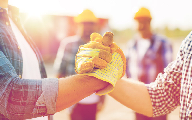 uilders hands in gloves greeting each other with handshake on construction site